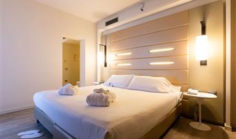 camera junior suite, circa 44 mq, 1 letto king size e 1 divano letto singolo, scrivania, free wifi, bollitore, accappatoio con ciabattine e set di cortesia, minibar con snack e soft drink, macchina segafredo, cassaforte, 2 tv lcd con canali sky e chromecast, parcheggio gratuito e palestra al 18° piano, benvenuto speciale (1 calice di vino con stuzzichini)